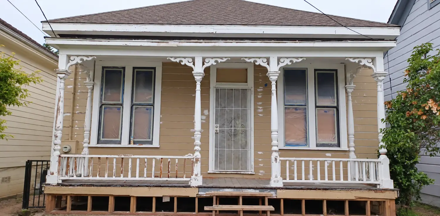 Historic Victorian before the rebuild, with peeling paint and an exposed foundation